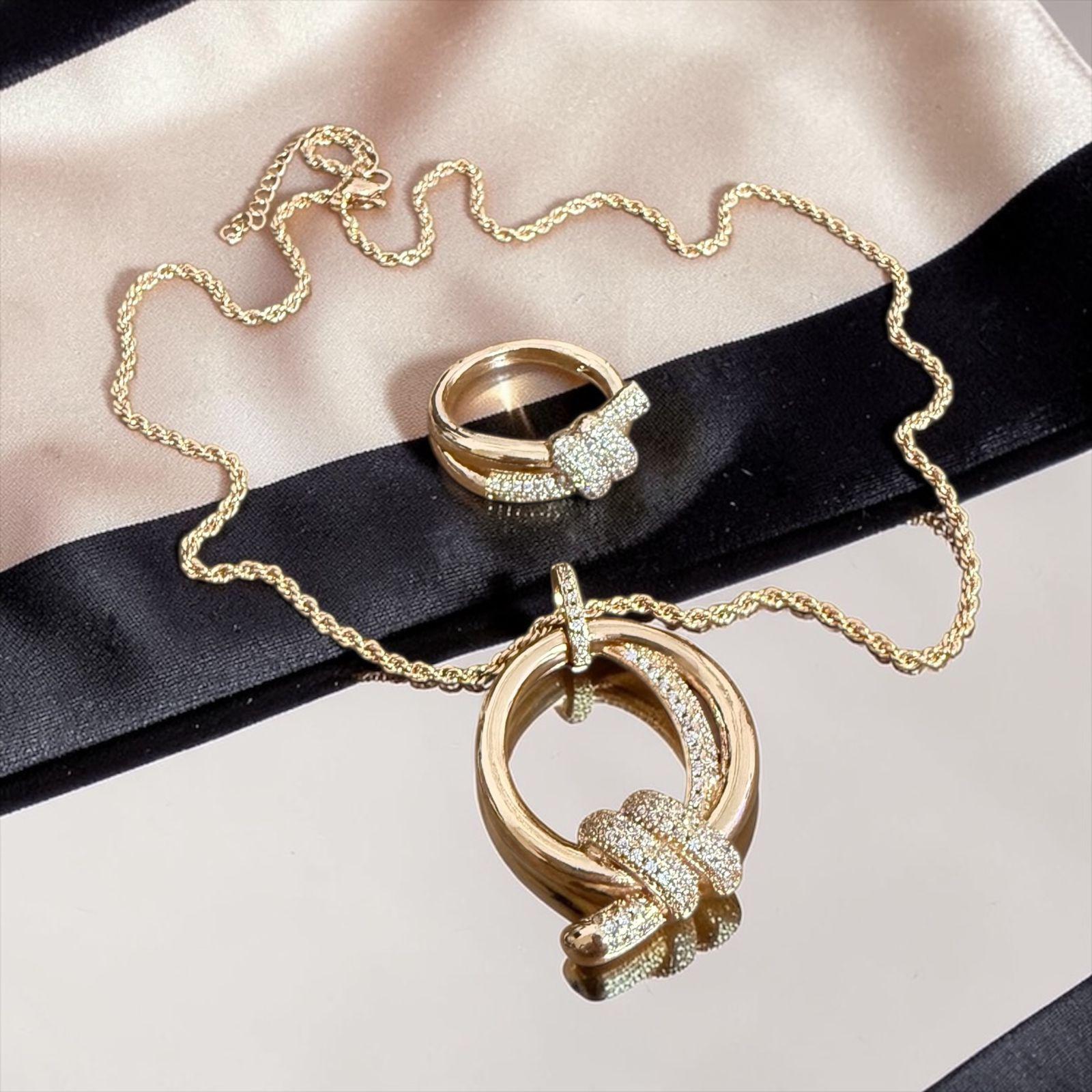 Conjunto Elo Dourado Lux Descrição: Conjunto sofisticado com colar e anel em design de elos modernos, com acabamento polido e detalhes cravejados em zircônias que trazem brilho e elegância na medida certa. Uma combinação marcante e contemporânea, perfeita para compor looks refinados com personalidade.