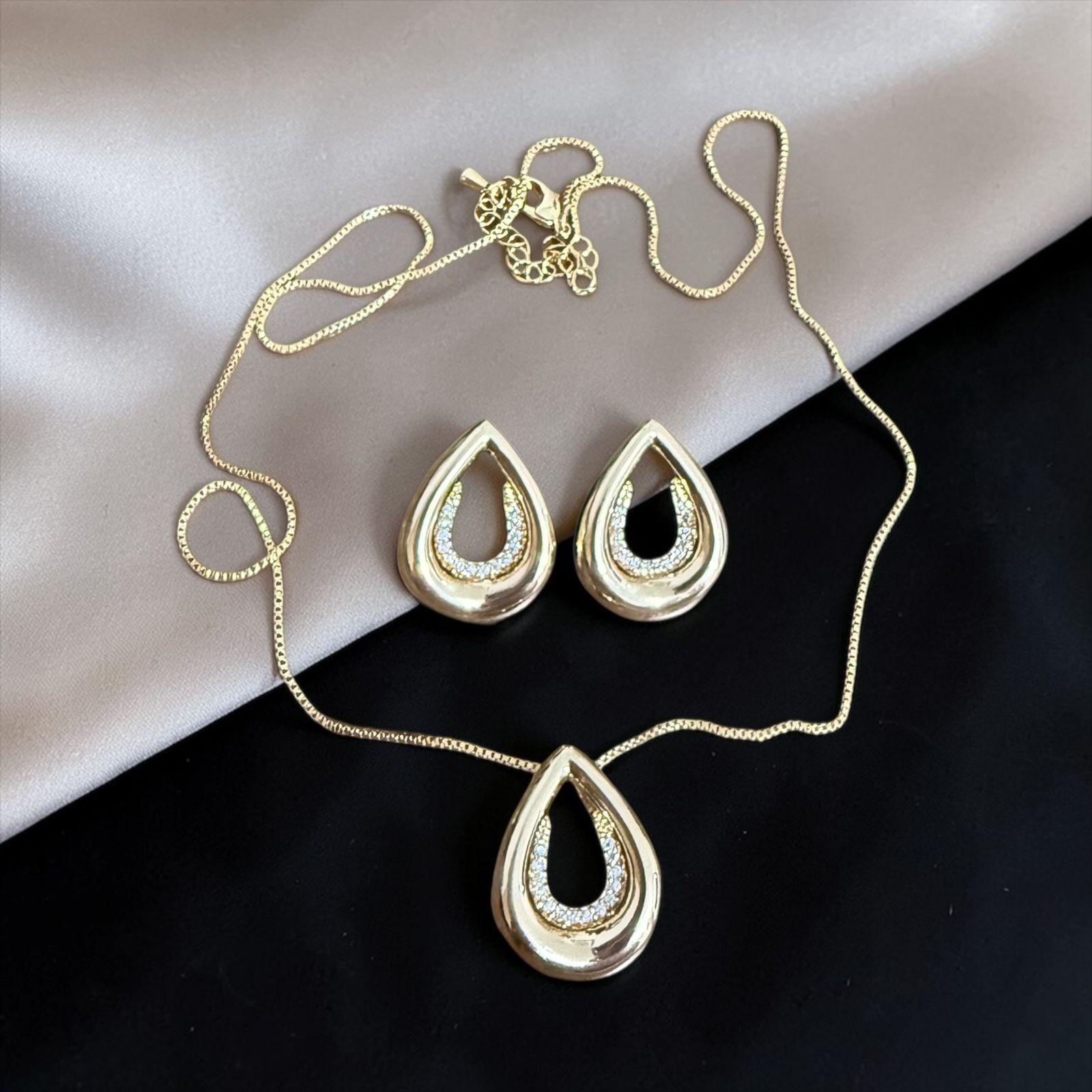Conjunto Gota Suprema Dourada Descrição: Curvas elegantes com acabamento dourado intenso e brilho interno em microcravação. Uma peça sofisticada e imponente, ideal para destacar sua presença com luxo e elegância.