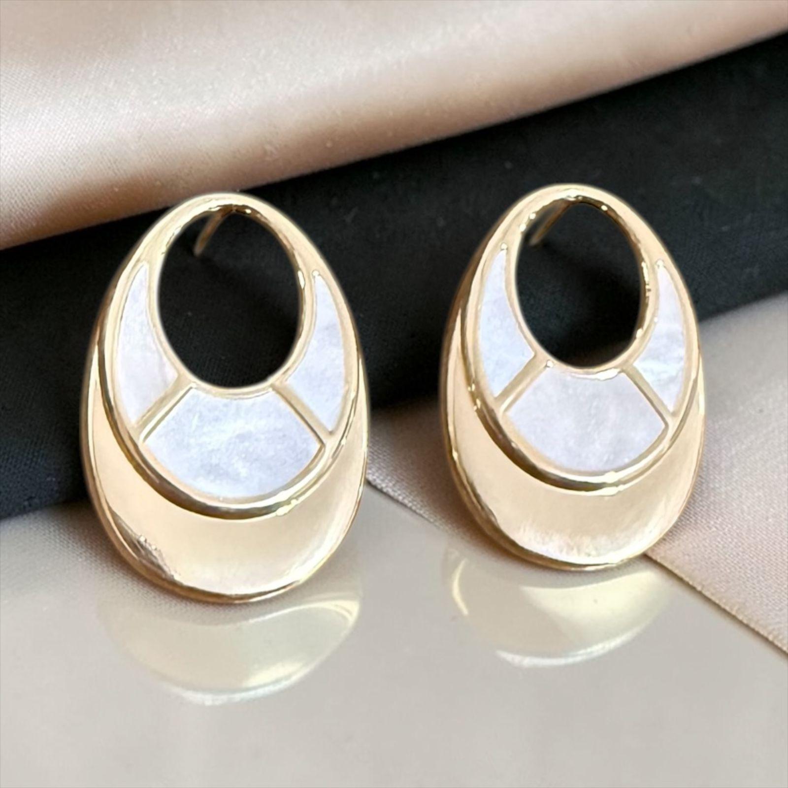 Brinco Aura Oval Madrepérola Descrição: Com design contemporâneo e acabamento sofisticado, este brinco une o dourado polido à delicadeza da madrepérola em um formato oval elegante. Uma peça leve e versátil que transmite sofisticação discreta para qualquer ocasião. 