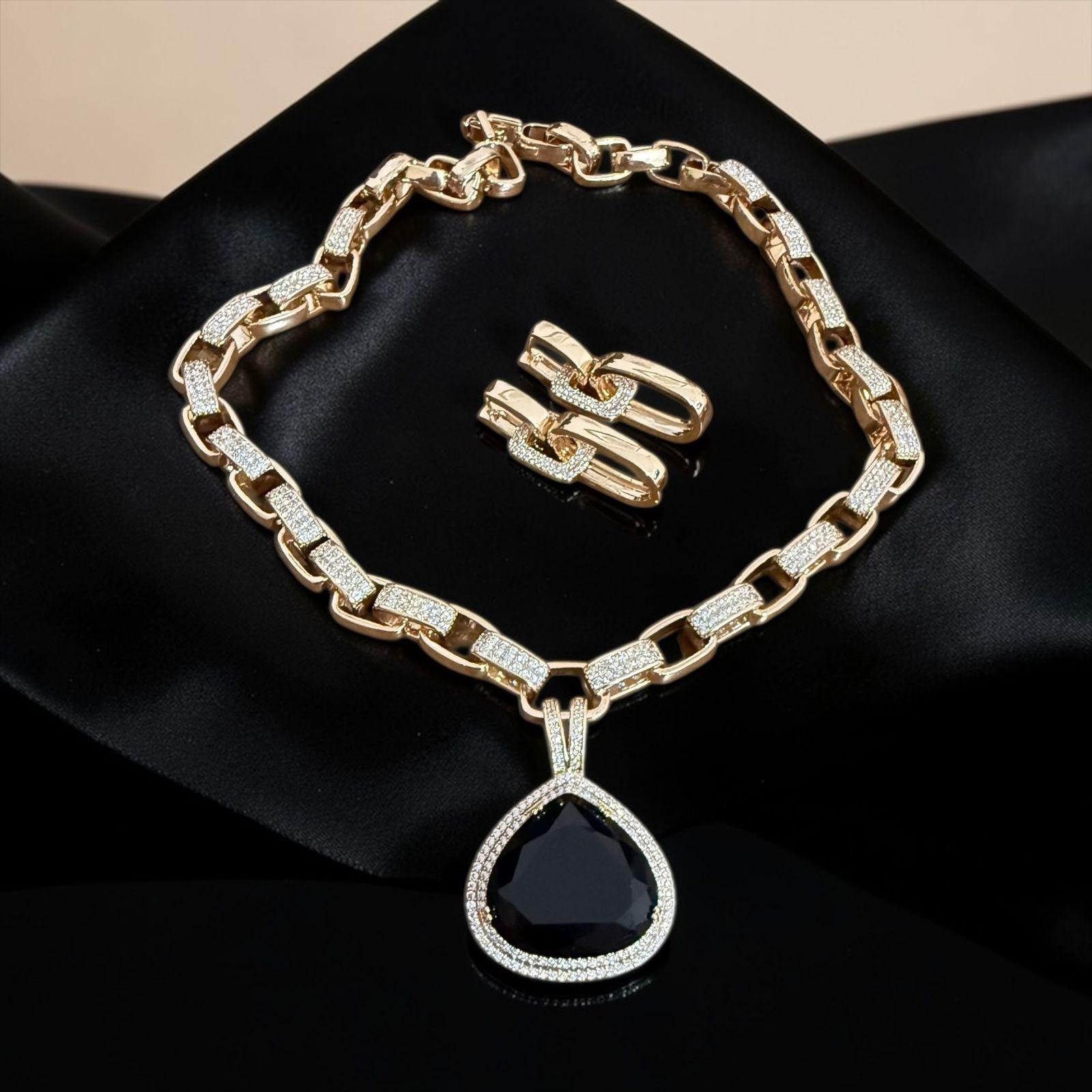 Conjunto Gota Noir Lux Descrição: Conjunto imponente com colar de elos robustos e pingente em gota com pedra negra central, envolvida por zircônias que realçam o brilho sofisticado. Acompanha brincos elegantes no mesmo estilo, criando uma composição poderosa, moderna e cheia de presença para ocasiões especiais
