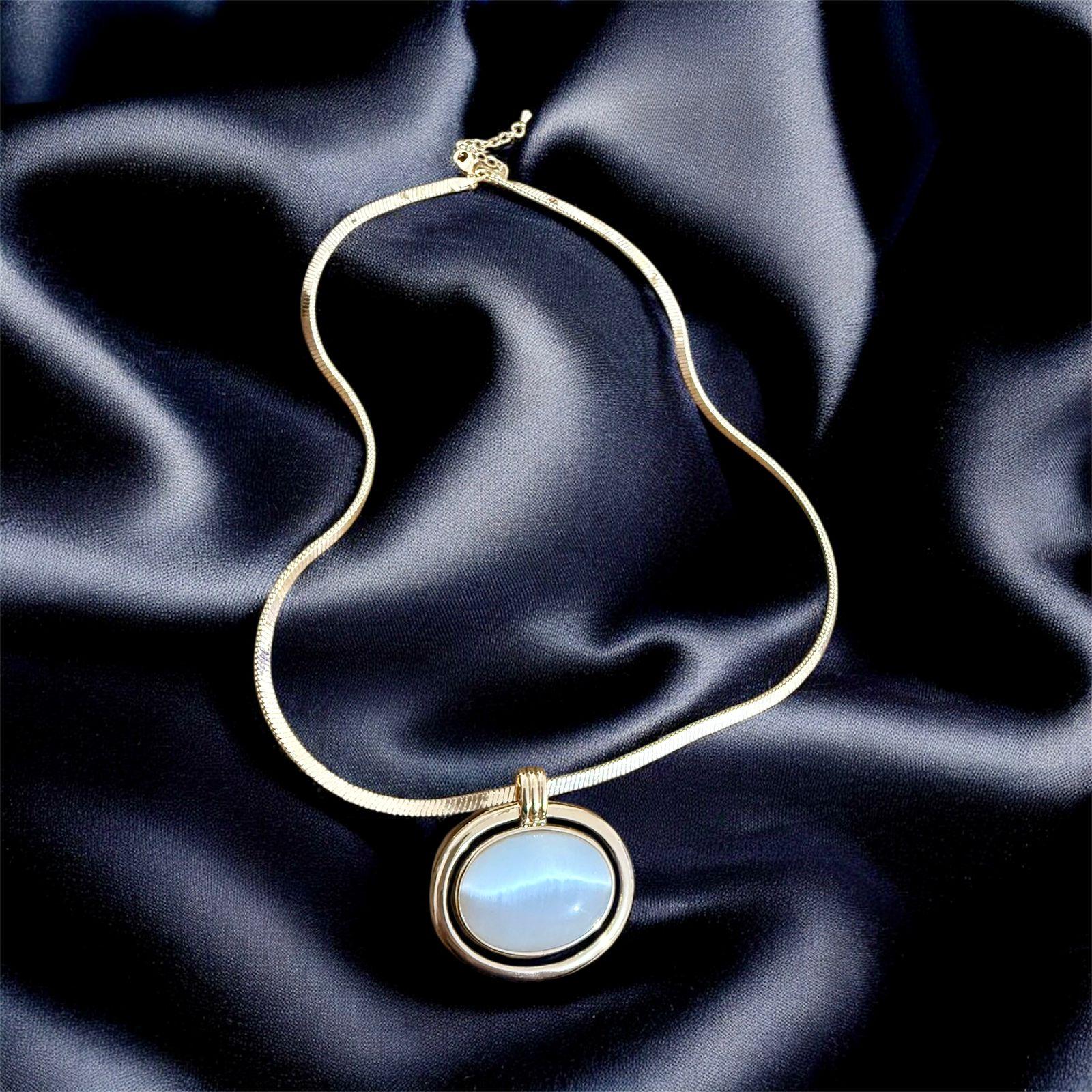 Colar Aura Lunar Descrição: Colar elegante com pingente oval em moldura marcante, perfeito para destacar produções refinadas.