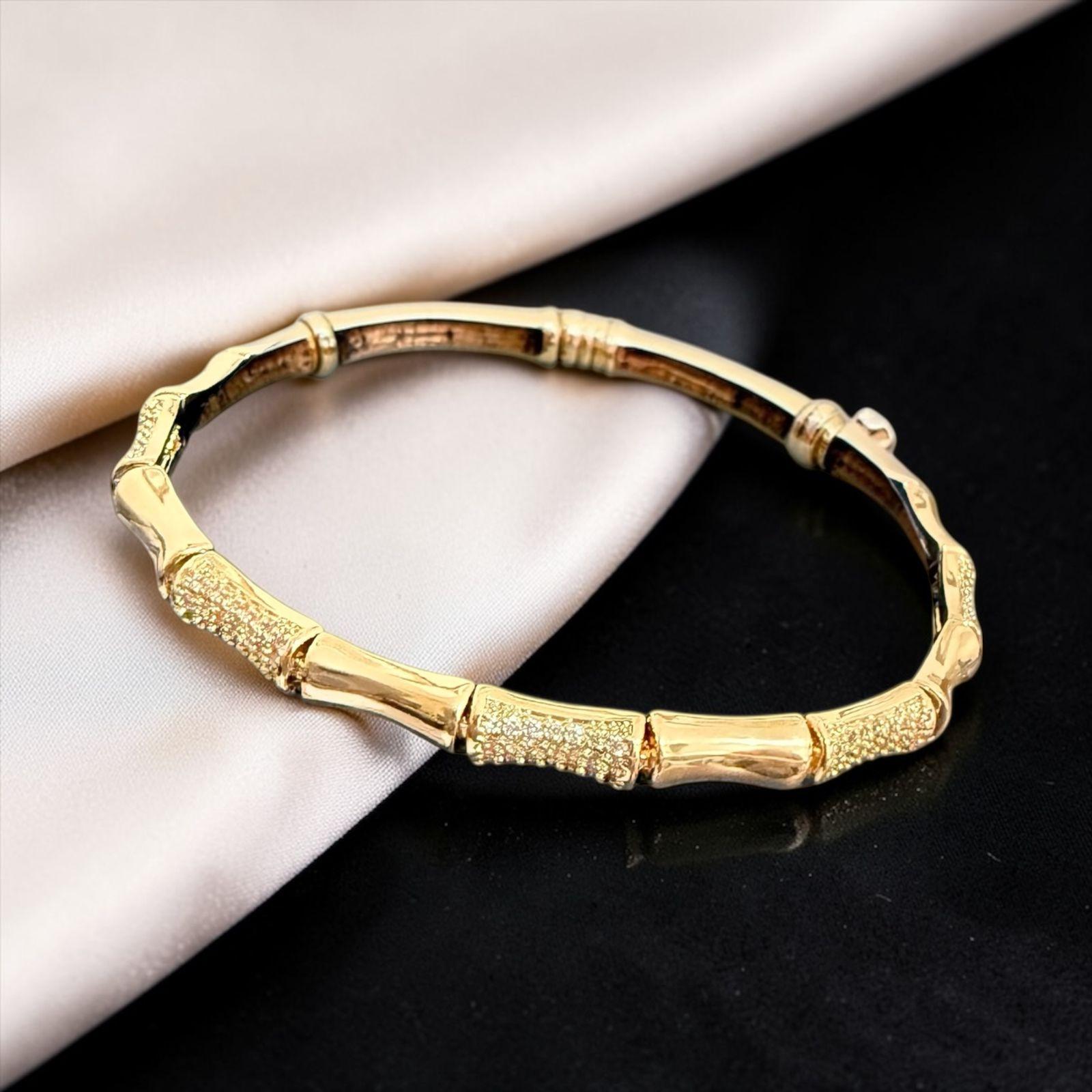 Pulseira Bamboo Dourado Descrição: Inspirado nas formas naturais do bambu, com acabamento dourado e detalhes texturizados que acrescentam brilho sutil. Um clássico elegante e atemporal, perfeito para composições sofisticadas.
