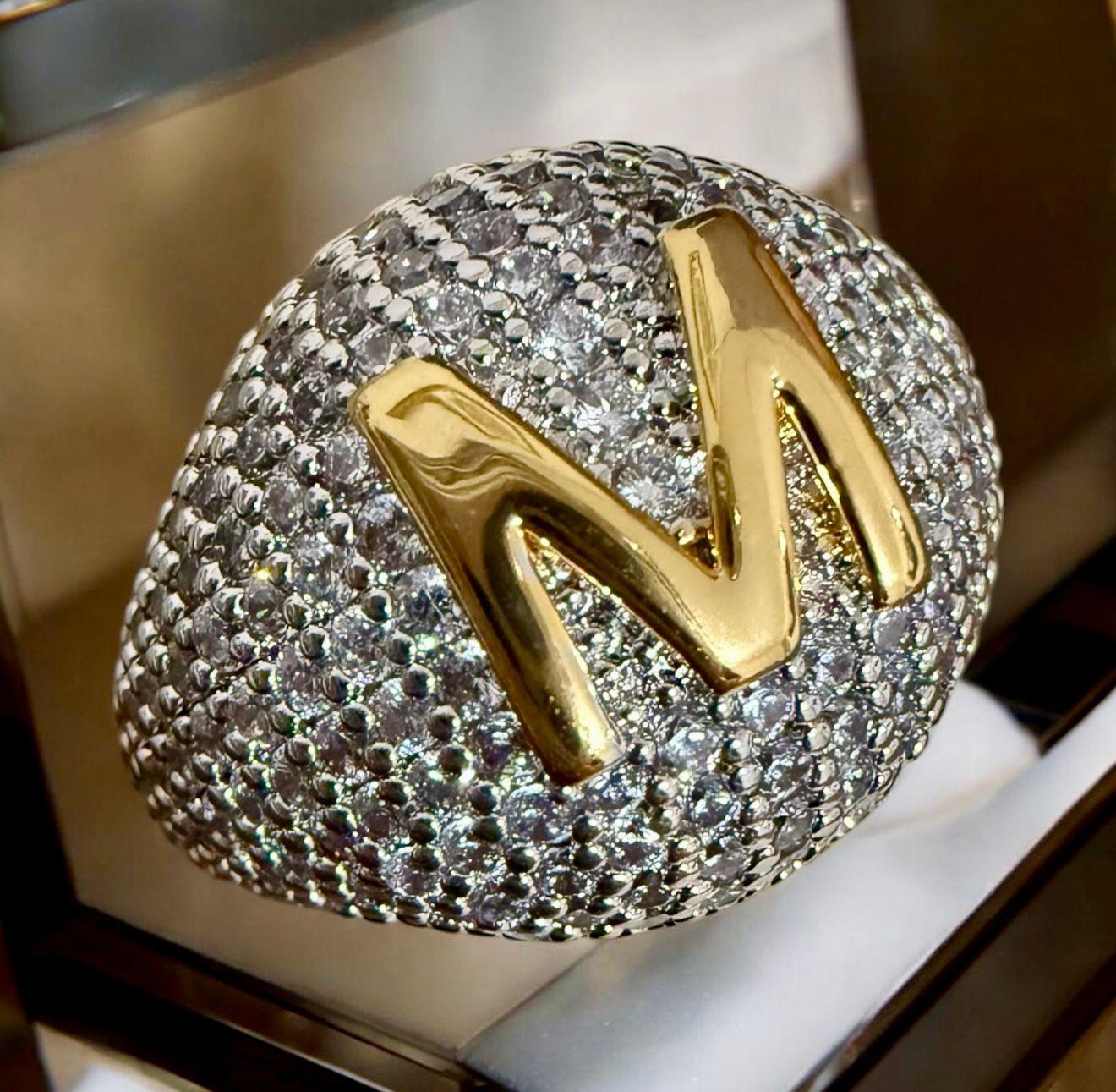 Anel Monograma M Glam - aro 18  Descrição: Anel imponente, totalmente cravejado com zircônias cintilantes e inicial M em alto relevo, finalizada em banho dourado. Ideal para quem valoriza exclusividade e sofisticação.