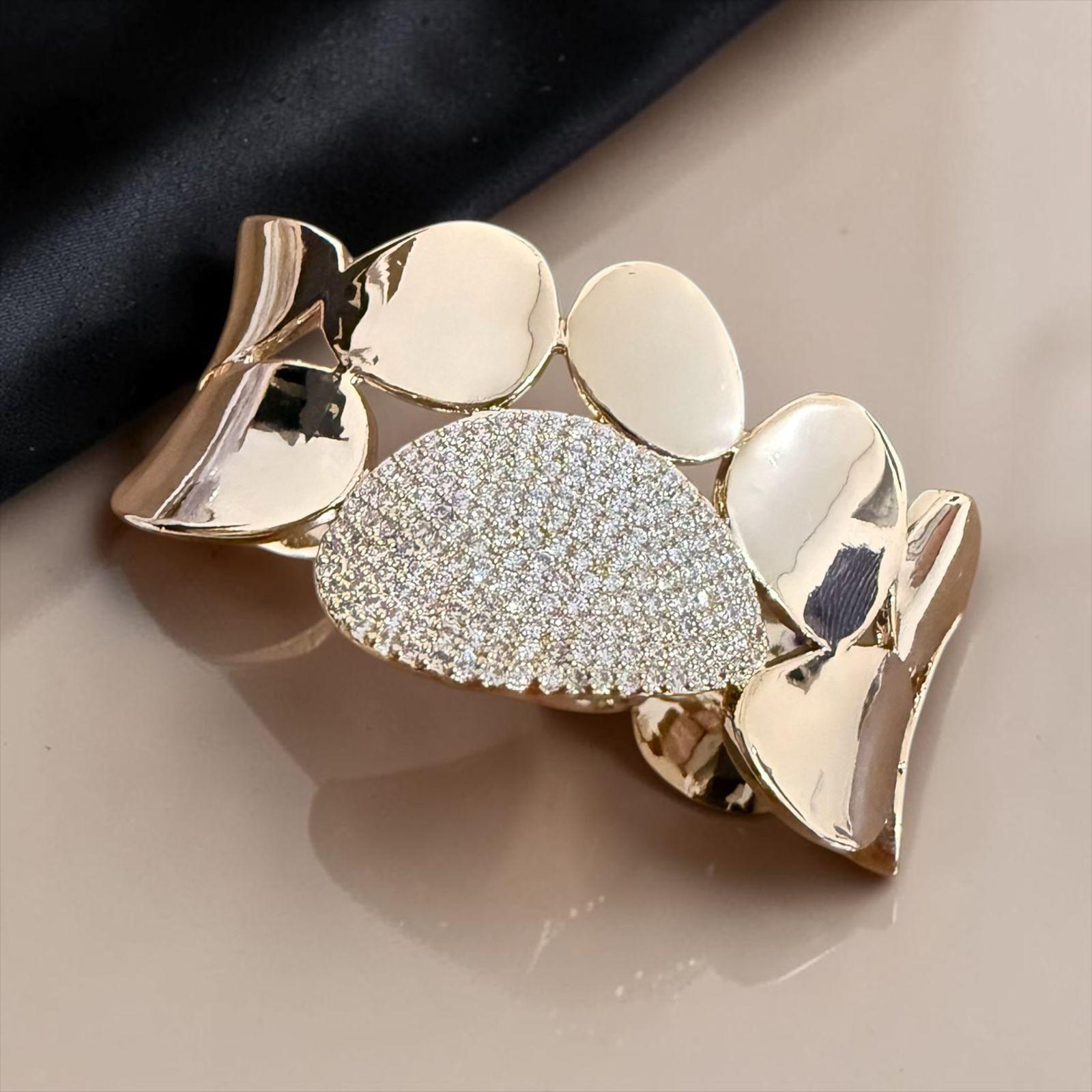 Bracelete Essenza Dourada Descrição: Bracelete com design orgânico e contemporâneo, composto por formas fluidas em acabamento dourado polido e destaque central texturizado de brilho intenso. Uma peça imponente e sofisticada, perfeita para quem busca elegância com personalidade e um toque artístico no visual.
