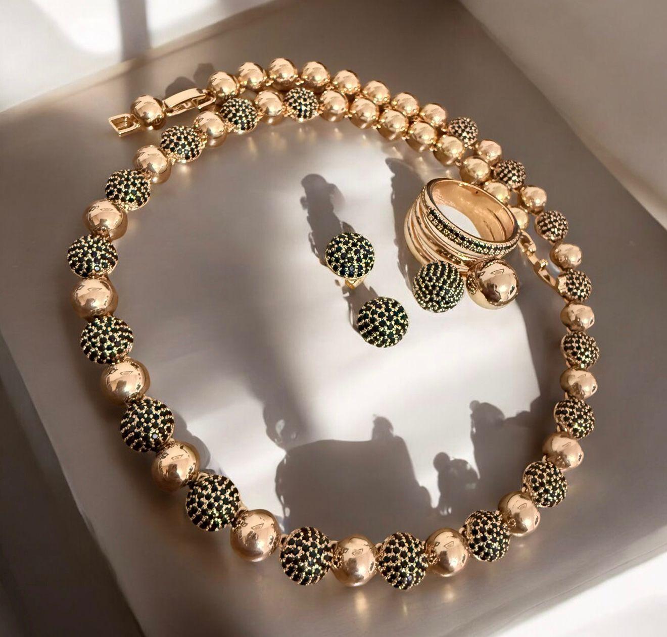 Conjunto Glam Noir Dourado - anel aro 16 Descrição: Colar, brincos e anel com esferas douradas e detalhes cravejados em tom escuro, que traduzem luxo e sofisticação contemporânea.