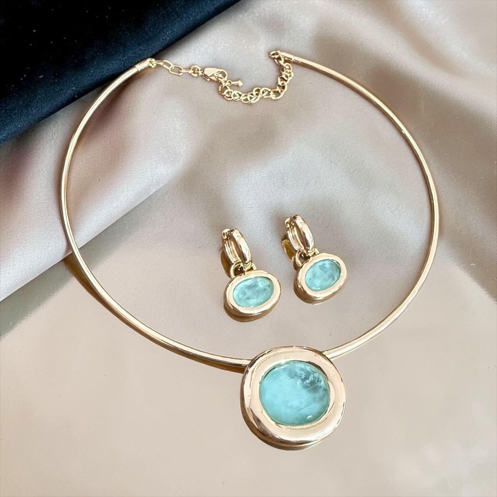 Conjunto Aura Turquesa Lux Descrição: Conjunto sofisticado com colar rígido e brincos delicados, destacando pedra em tom turquesa com acabamento polido e moldura dourada elegante. Uma combinação leve e refinada, perfeita para iluminar o visual com frescor, elegância e um toque de cor sofisticada.
