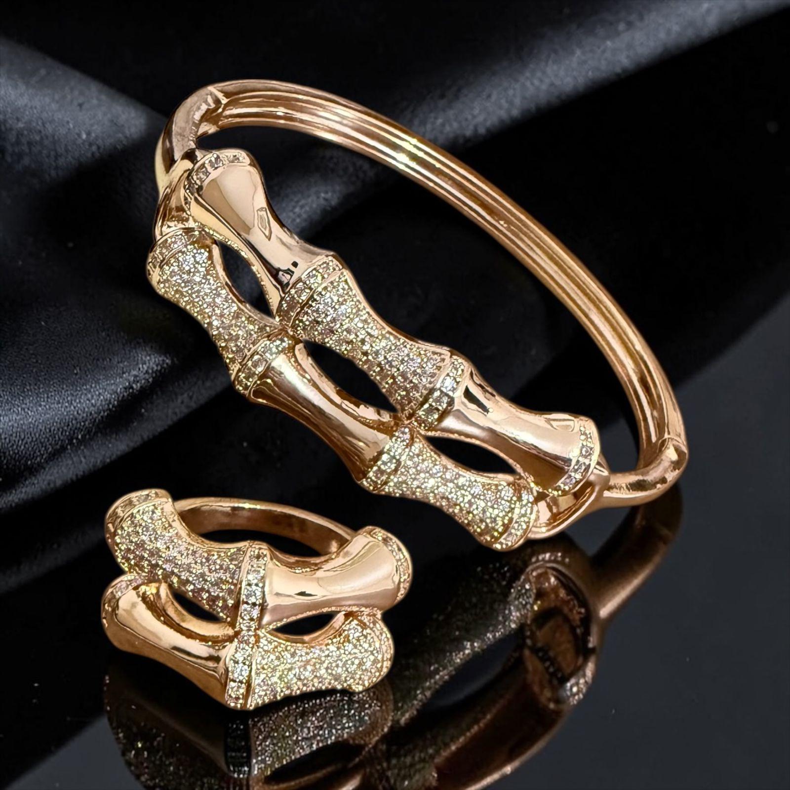 Conjunto Laço Imperial Lux Descrição: Conjunto sofisticado com bracelete e anel em design de laço entrelaçado, com acabamento polido e detalhes cravejados em zircônias que realçam o brilho com elegância. Uma peça marcante e feminina, perfeita para compor looks refinados com um toque de delicadeza e poder.
