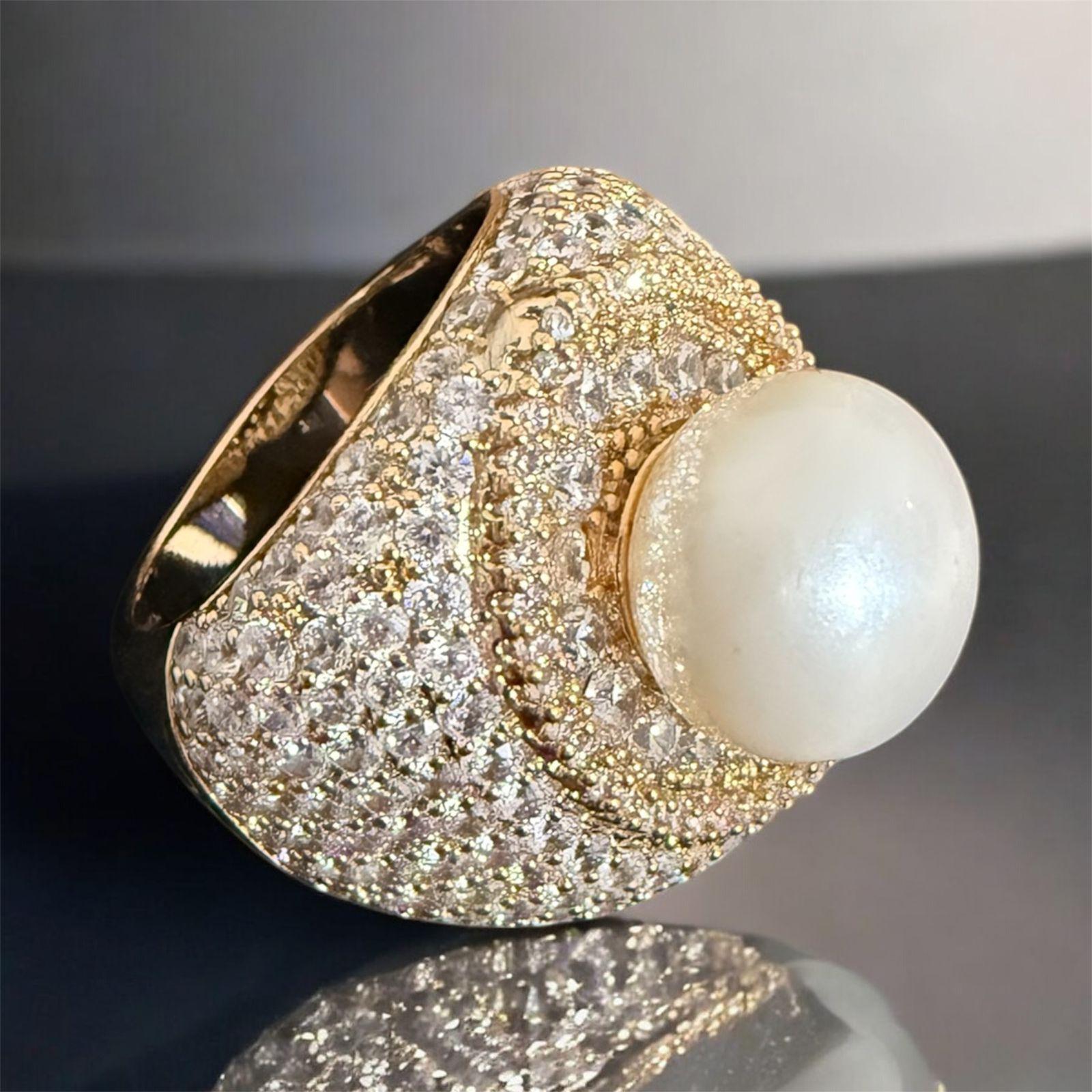 Anel Aurora Pérola - aro 20 Descrição: Anel sofisticado em banho dourado, com zircônias cintilantes e pérola central de acabamento acetinado, que traduz elegância, brilho e requinte em uma peça de destaque.