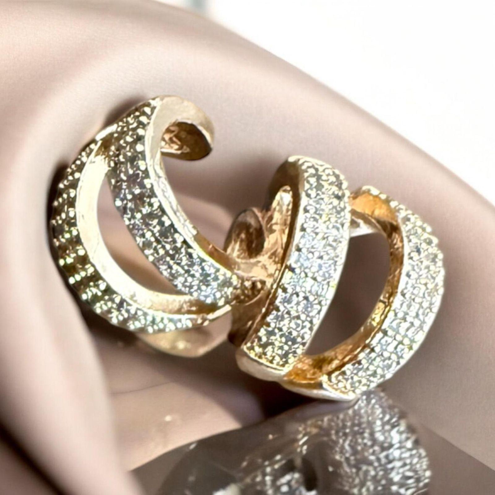 Argola Luxo Brilho Descrição: Argolas sofisticadas com acabamento dourado e superfície cravejada de microcristais. Uma peça clássica e elegante que ilumina qualquer produção.