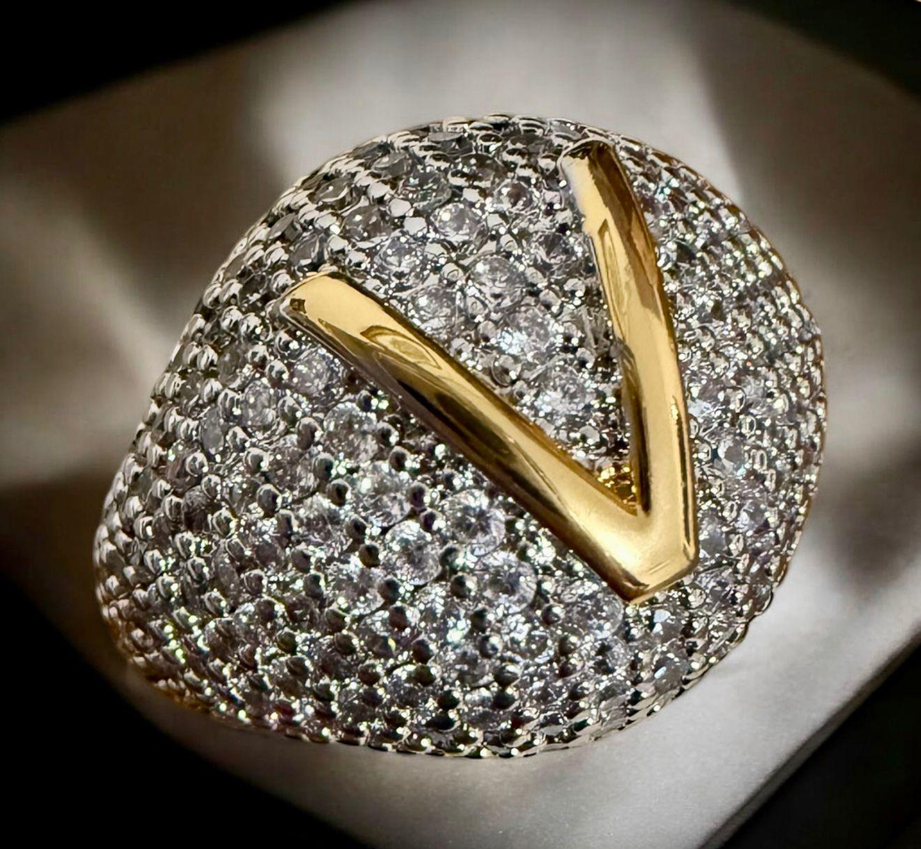 Anel Monograma V Glam - aro 18 Descrição: Anel imponente, totalmente cravejado com zircônias cintilantes e inicial V em alto relevo, finalizada em banho dourado. Ideal para quem busca exclusividade e sofisticação.